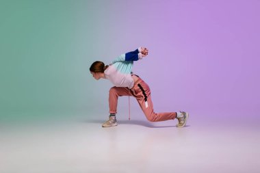 Neon ışıklarıyla dans eden, dans salonunun arka planında şık giysiler içinde hip-hop yapan kız..