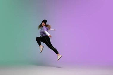 Neon ışıklarıyla dans eden, dans salonunun arka planında şık giysiler içinde hip-hop yapan kız..
