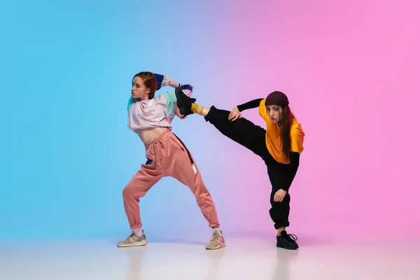 Mädchen tanzen Hip-Hop in stylischer Kleidung auf Steigungsuntergrund im Tanzsaal in Neonlicht. — Stockfoto