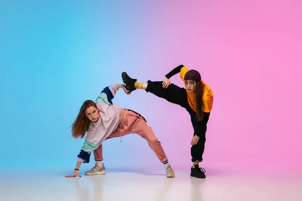 Дівчата танцюють хіп-хоп у стильному одязі на градієнтному фоні в танцювальному залі в неоновому світлі . — стокове фото