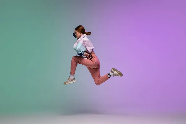 Chica bailando hip-hop en ropa elegante sobre fondo degradado en el salón de baile en luz de neón . — Foto de Stock