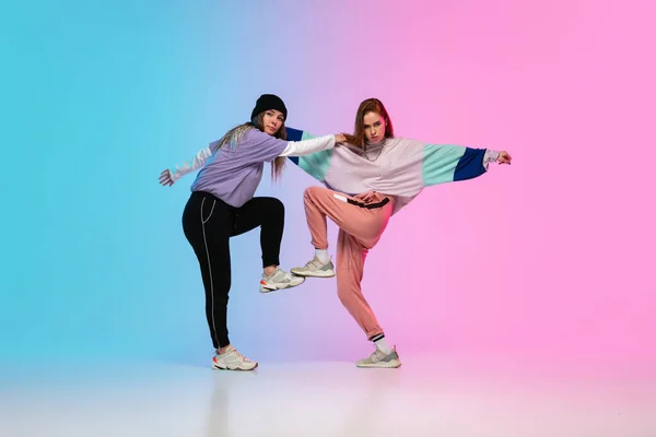 Chicas bailando hip-hop con ropa elegante sobre fondo degradado en el salón de baile en luz de neón . — Foto de Stock