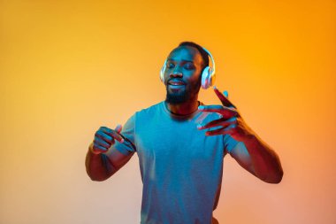 Afro-Amerikan erkek portresi, neon ışıklı arka planda izole edilmiş turuncu stüdyo.