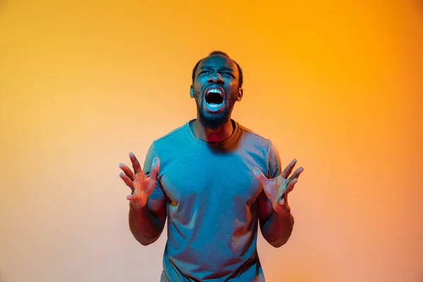 Afrikkalais-amerikkalainen mies muotokuva eristetty kaltevuus oranssi studio tausta neon valossa — kuvapankkivalokuva