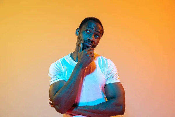 Retrato de hombre afroamericano aislado sobre fondo de estudio naranja degradado en luz de neón —  Fotos de Stock