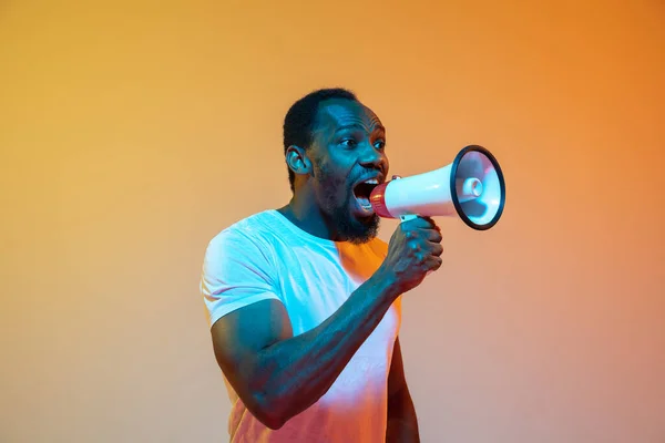 African-american mans portrait isolated on gradient orange studio background in neon light