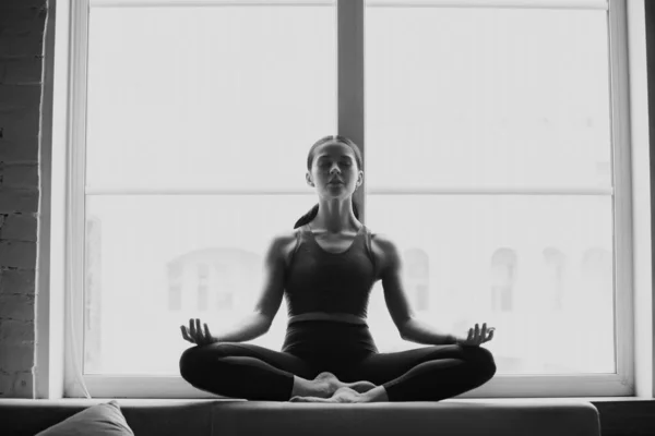 Mujer joven y deportiva practicando yoga en casa — Foto de Stock