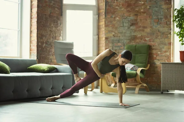 Mujer joven y deportiva practicando yoga en casa — Foto de Stock
