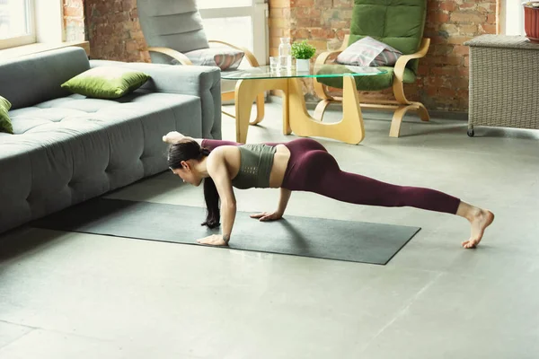 Sportos fiatal nő jógázik otthon — Stock Fotó