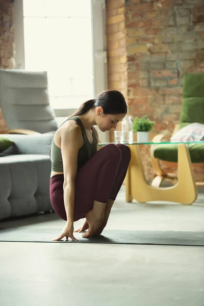 Mujer joven y deportiva practicando yoga en casa — Foto de Stock