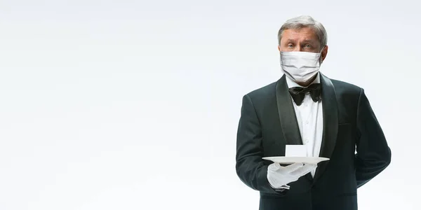 Елегантність старшого чоловіка офіціанта в захисній масці для обличчя на білому тлі. Флаєр з копійкою . — стокове фото