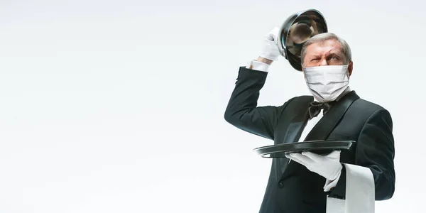 Eleganza uomo anziano cameriere in maschera protettiva su sfondo bianco. Volantino con copyspace . — Foto Stock