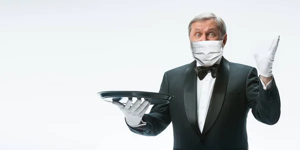 Elegância garçom homem sênior em máscara protetora no fundo branco. Folheto com copyspace . — Fotografia de Stock