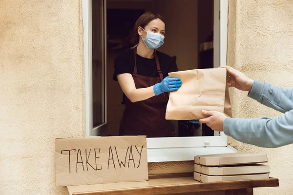 Kobieta przygotowuje napoje i posiłki, nosi maskę ochronną i rękawiczki. Bezdotykowy serwis dostawy podczas pandemii koronawirusowej kwarantanny. Zabierz tylko koncepcję.. — Zdjęcie stockowe