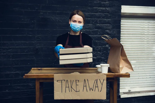 Mujer preparando bebidas y comidas, usando mascarilla protectora y guantes. Servicio de entrega sin contacto durante la pandemia del coronavirus de cuarentena. Quitar solo concepto . — Foto de Stock