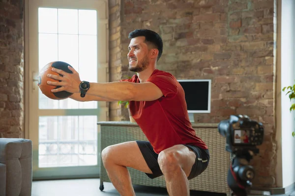 Jonge blanke man training thuis tijdens quarantaine van coronavirus uitbraak, het doen van oefeningen van fitness, aërobe. Sportief blijven tijdens isolatie. — Stockfoto