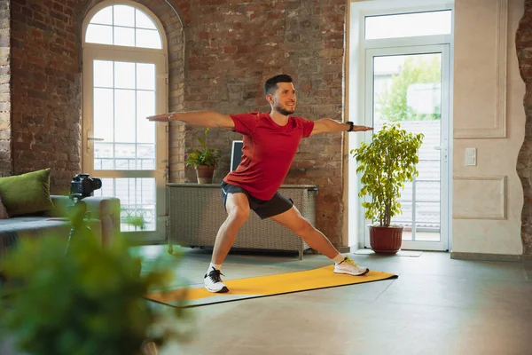 Koronavirüs salgını karantinası sırasında evde antrenman yapan genç beyaz adam spor yapıyor, aerobik yapıyor. İzolasyon sırasında sportif kalmak. — Stok fotoğraf