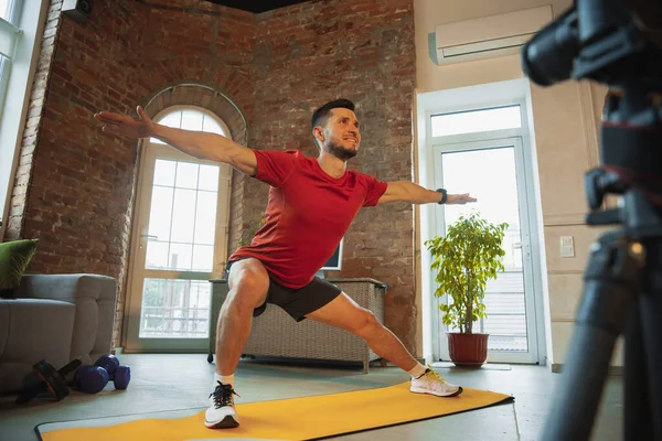 Junge kaukasische Mann Training zu Hause während der Quarantäne von Coronavirus Ausbruch, Übungen der Fitness, Aerobic. Während der Isolierung sportlich bleiben. — Stockfoto