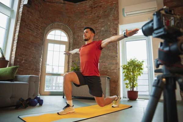 Jonge blanke man training thuis tijdens quarantaine van coronavirus uitbraak, het doen van oefeningen van fitness, aërobe. Sportief blijven tijdens isolatie. — Stockfoto