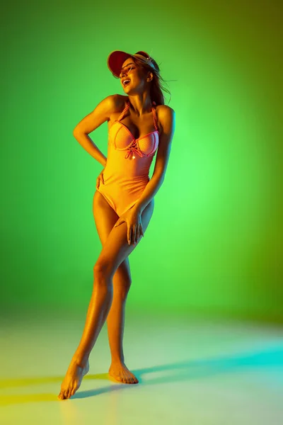 Красива дівчина в модному купальнику ізольована на градієнтному студійному фоні в неоновому світлі. Літо, курорт, мода і концепція вихідних — стокове фото