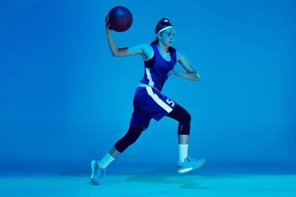 若いです白人女性バスケットボール選手はネオンライトで青のスタジオの背景に隔離 — ストック写真