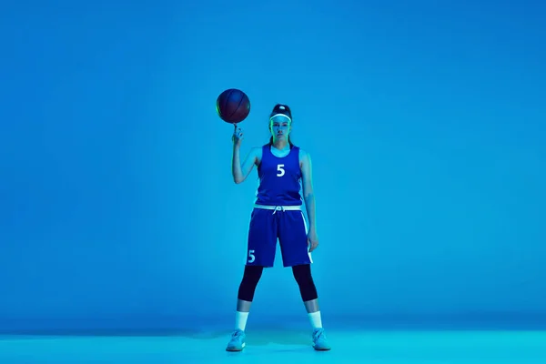 Joven jugador de baloncesto femenino caucásico aislado en fondo estudio azul en luz de neón —  Fotos de Stock