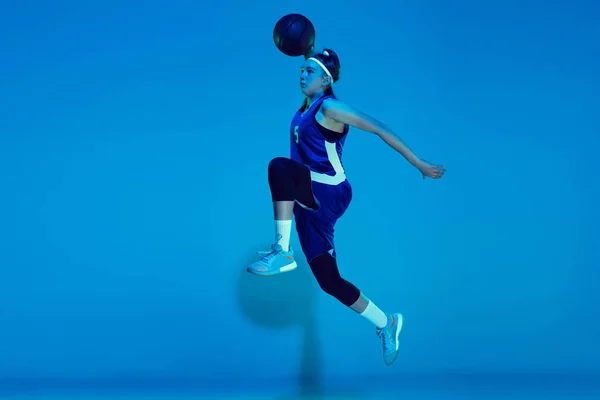 Молода біла баскетболістка ізольована на синьому студійному фоні в неоновому світлі — стокове фото