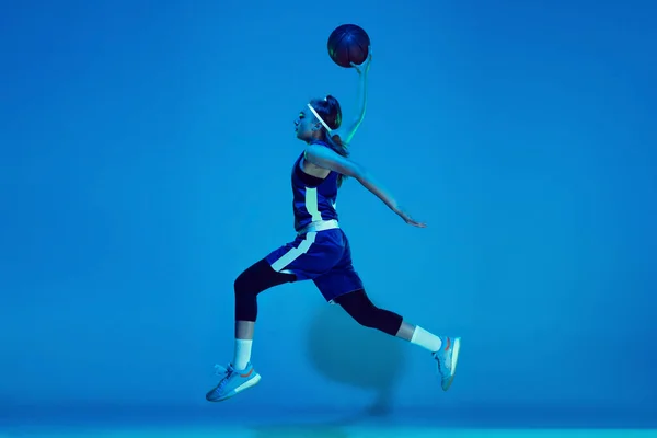 Giovane giocatore di basket femminile caucasico isolato su sfondo blu studio in luce al neon — Foto Stock