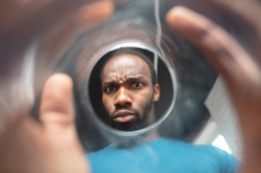 Afro-Amerikalı bir adam evinde alışılmadık yerlerde iş arıyor.