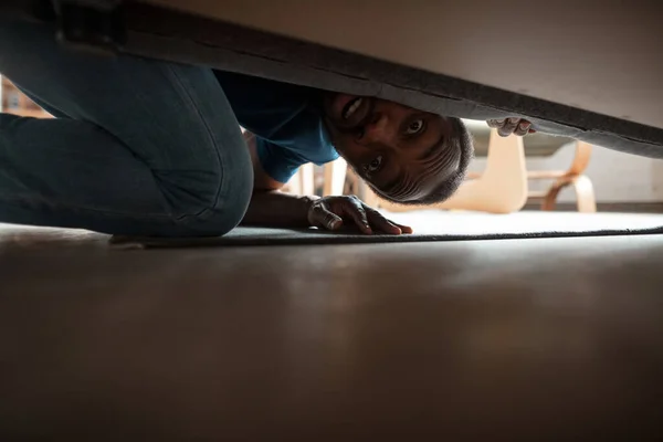 Afrikai-amerikai férfi munkát keres szokatlan helyeken az otthonában. — Stock Fotó