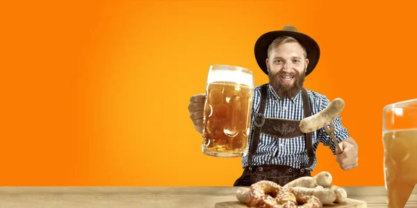 Hombre sonriente con cerveza vestida con traje tradicional austriaco o bávaro sosteniendo jarra de cerveza en un pub o estudio. La celebración, oktoberfest, festival —  Fotos de Stock