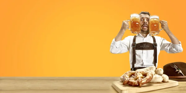 Hombre sonriente con cerveza vestida con traje tradicional austriaco o bávaro sosteniendo jarra de cerveza en un pub o estudio. La celebración, oktoberfest, festival —  Fotos de Stock