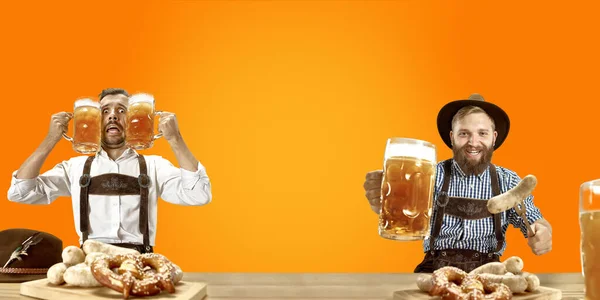 Hombres sonrientes con cerveza vestidos con el traje tradicional austriaco o bávaro sosteniendo taza de cerveza en un pub o estudio. La celebración, oktoberfest, festival —  Fotos de Stock