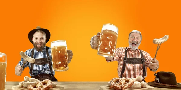 Mosolygó férfiak sör öltözött hagyományos osztrák vagy bajor jelmez kezében bögre sört kocsmában vagy stúdióban. Ünnepség, oktoberfest, fesztivál — Stock Fotó