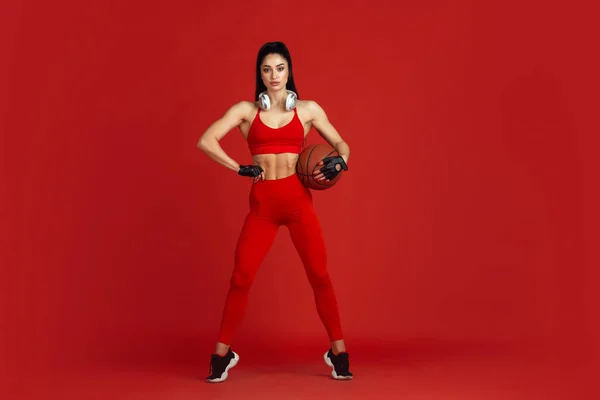 Bonita jovem atleta praticando no fundo estúdio vermelho, retrato monocromático — Fotografia de Stock