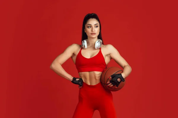 Gyönyörű fiatal női sportoló gyakorló piros stúdió háttér, monokróm portré — Stock Fotó