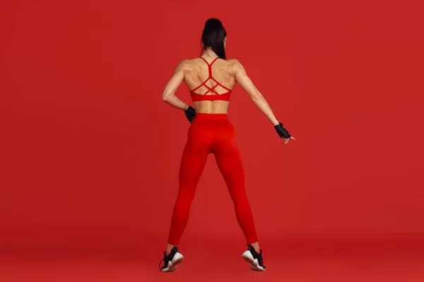 Belle jeune athlète féminine pratiquant sur fond de studio rouge, portrait monochrome — Photo