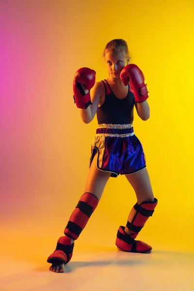 Pouco caucasiano feminino kick boxer treinamento em fundo gradiente em luz de néon, ativo e expressivo — Fotografia de Stock