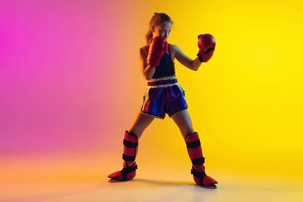 Pequeño entrenamiento de boxeador femenino caucásico sobre fondo degradado en luz de neón, activo y expresivo — Foto de Stock