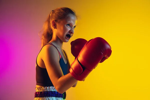 Pequeño entrenamiento de boxeador femenino caucásico sobre fondo degradado en luz de neón, activo y expresivo — Foto de Stock