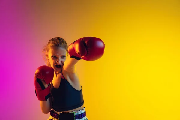 Weinig blanke vrouwelijke kick bokser training op gradiënt achtergrond in neon licht, actief en expressief — Stockfoto