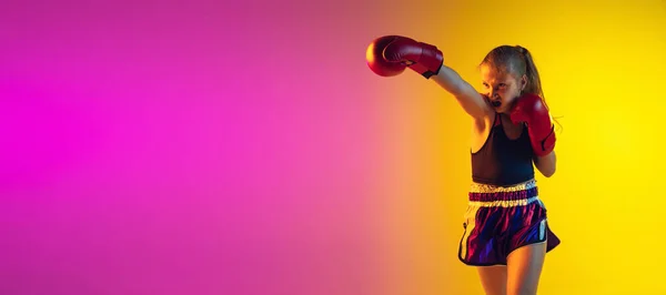 Kleine kaukasische Kickboxerin trainiert auf Gradienten-Hintergrund in Neonlicht, aktiv und ausdrucksstark — Stockfoto