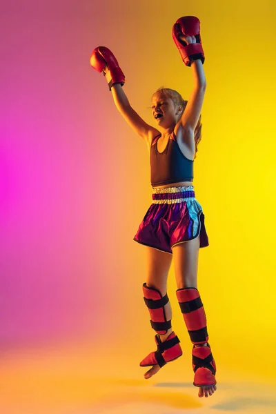 霓虹灯下渐变背景下的小高加索女踢腿拳击手训练，活跃且有表现力 — 图库照片