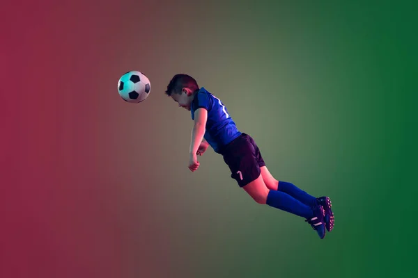 Teen male football or soccer player, boy on gradient background in neon light - motion, action, activity concept — Stock Photo, Image