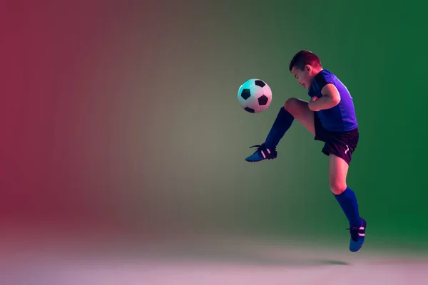 Teen male football or soccer player, boy on gradient background in neon light - motion, action, activity concept — Stock Photo, Image