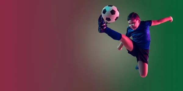 Giocatore di calcio o calcio maschile adolescente, ragazzo su sfondo sfumato in luce al neon movimento, azione, concetto di attività — Foto Stock
