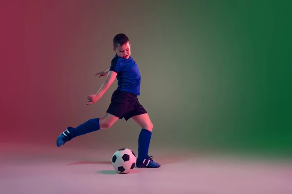 Giocatore di calcio o calcio maschile adolescente, ragazzo su sfondo sfumato in luce al neon movimento, azione, concetto di attività — Foto Stock