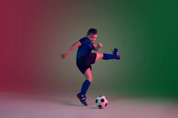 Adolescente futebol masculino ou jogador de futebol, menino em fundo gradiente em luz de néon - movimento, ação, conceito de atividade — Fotografia de Stock