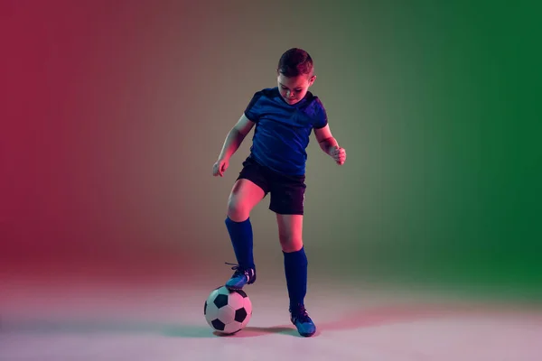 Giocatore di calcio o calcio maschile adolescente, ragazzo su sfondo sfumato in luce al neon movimento, azione, concetto di attività — Foto Stock