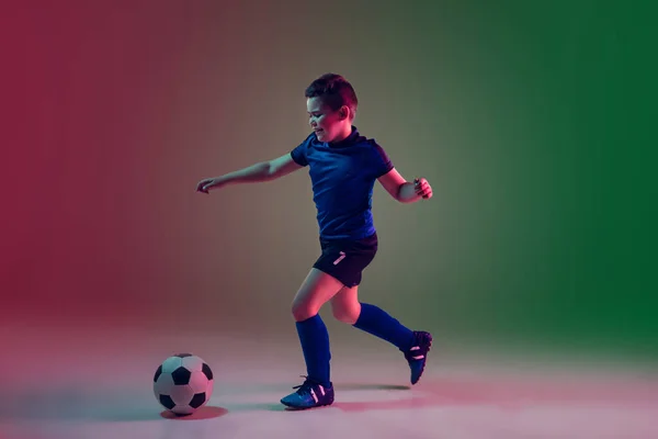 Teen male football or soccer player, boy on gradient background in neon light - motion, action, activity concept — Stock Photo, Image